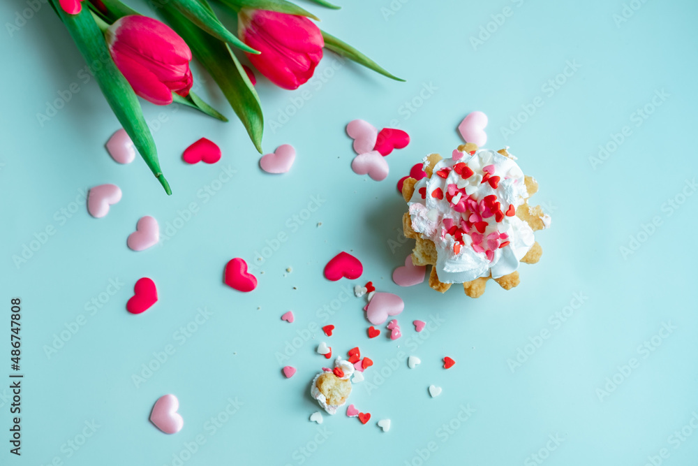 cake with whipped cream and red tulips on a blue background, top view cake with whipped cream and red tulips on a blue background, top view