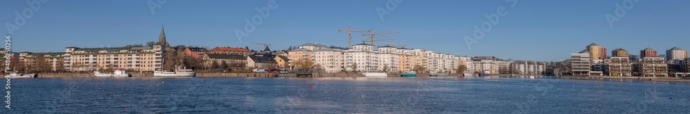 Panorama view, boats and modern apartment houses at the piers in the districts around the bay Hammarby sjö in the district Södermalm a sunny winter day in Stockholm