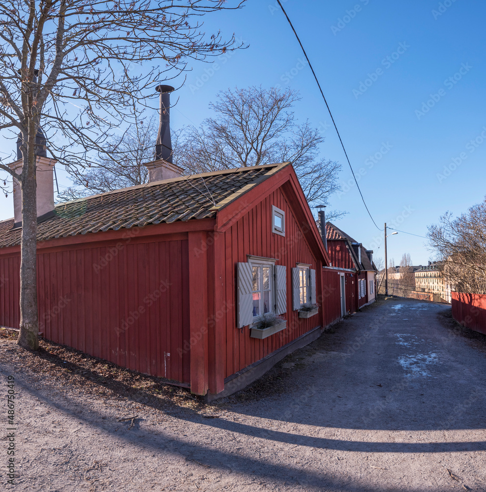 Obraz premium Old red heritage buildings, 1700s houses and the church Sofia Kyrka, in the district Södermalm a sunny winter day in Stockholm