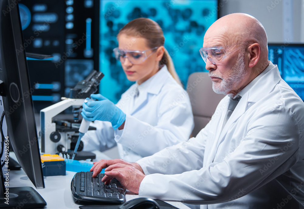 Professor and doctor work in a modern scientific laboratory using equipment and computertechnologies. Group of scientists make research and develop new vaccines. Science and healthcare concept.