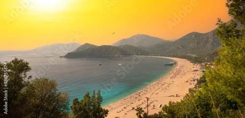 Fototapeta Naklejka Na Ścianę i Meble -  Amazing view of beautiful sunset Blue Lagoon in Oludeniz. Summer landscape with beach and mountains, azure water, sandy beach and orange sky. It is one of the most popular beaches in Turkey