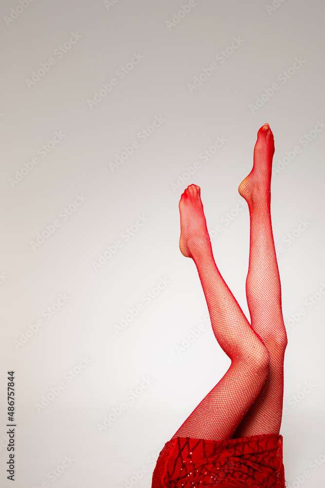 Legs up; Closeup slim legs of a woman in red pantyhose or sheer tights  covered with crystals or gemstones; on white background Stock Photo
