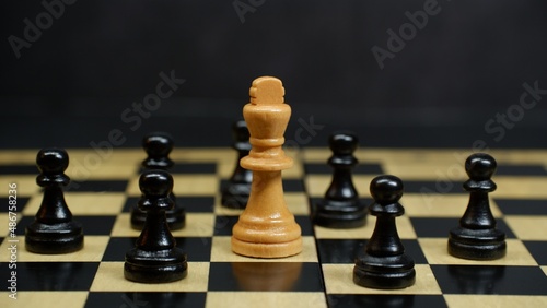 white king chess piece surrounded by black pawn chess pieces