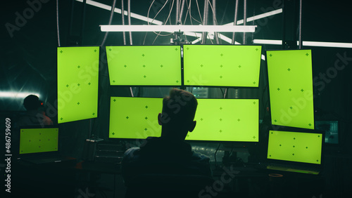 Wallpaper Mural Zoom in view unrecognizable man writing malicious code on computers while sitting against computer monitors with chromakey screens in dark room of hacker base Torontodigital.ca