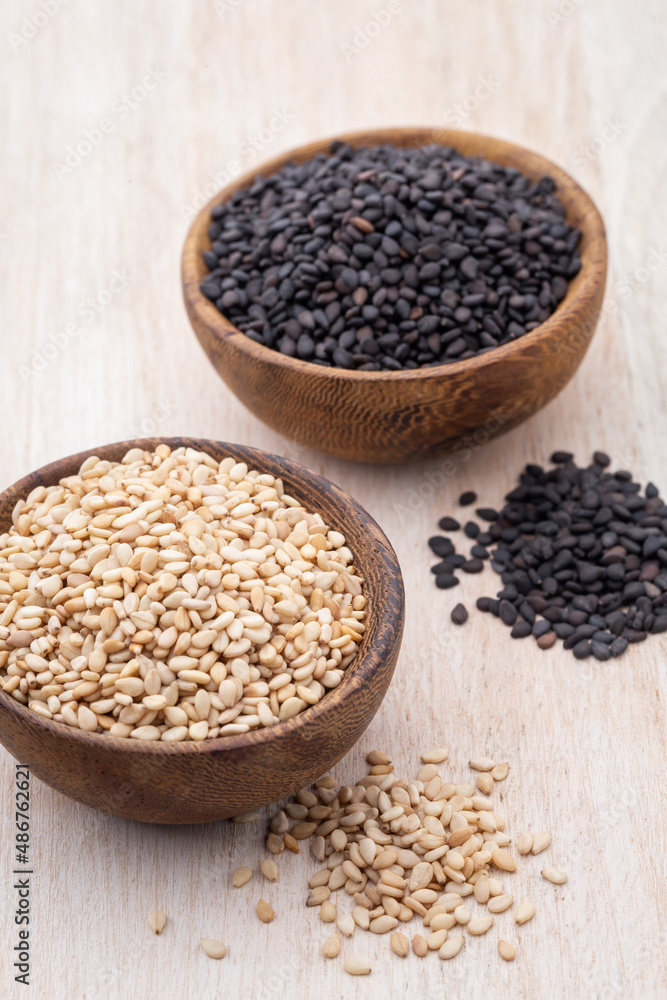 White sesame and black sesame seed on wooden bowl. White sesame and black sesame seed on wooden bowl.
