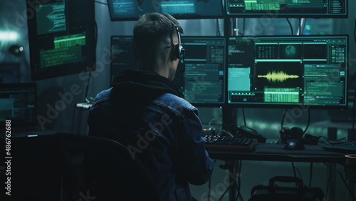 Billede på lærred Cheerful male hacker in headset rejoicing in a successful cyber attack in a dim
