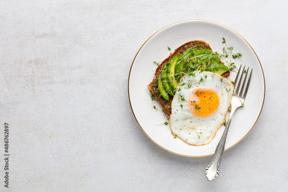 Keto breakfast fried egg, avocado and bread in a white plate. Keto diet concept. Keto breakfast fried egg, avocado and bread in a white plate. Keto diet concept.