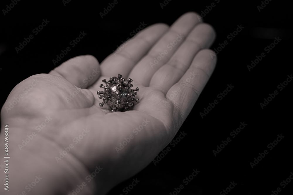 The man has a virus in his hand. A powerful angry virus with a face. The coronavirus is slightly blurred. The man has a virus in his hand. A powerful angry virus with a face. The coronavirus is slightly blurred.