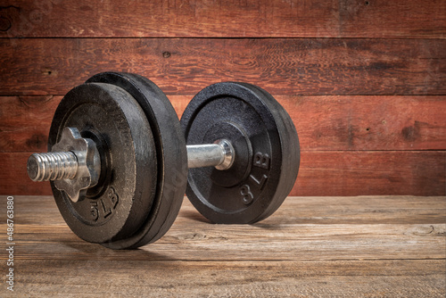 cast iron dumbbell on a grunge wooden deck - fitness concept