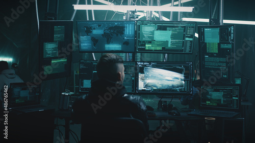 A male hacker in a casual jacket on a chair, hacking a nuclear weapon launch on a computer with a countdown in a dark cybercriminal hideout