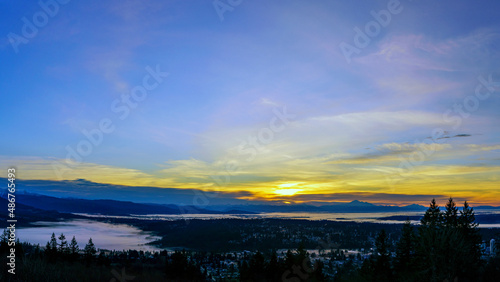 Sunrise over BC valley carpeted with low lying cloud inversion, with mountains in silhouette on horizon. © Andrew