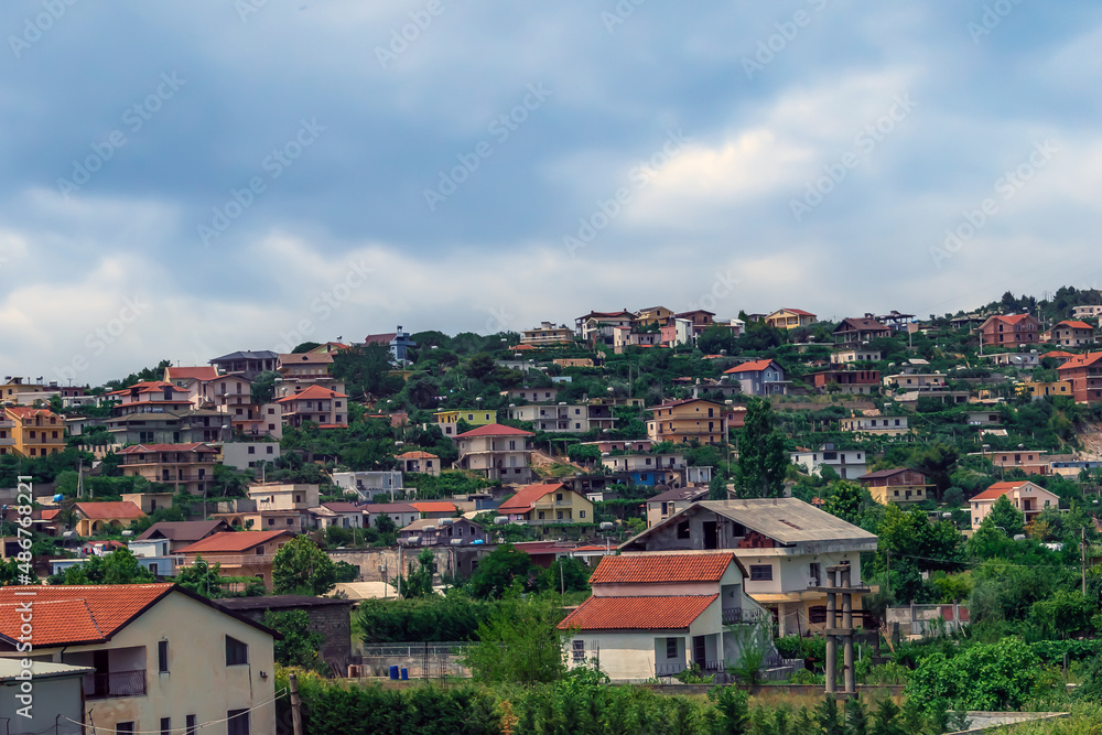 Panorama of Lezhe city on a mountain slope in Albania. Rustic European landscape with villas among summer greenery on a hillside