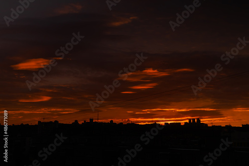 Colorful orange sunrise over city and dramatic sky with clouds - sun goes up  warm illumination. Nature  urban  morning  peaceful  atmospheric view concept