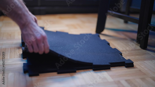 Person preparing rubber flooring material for exercise protection at home