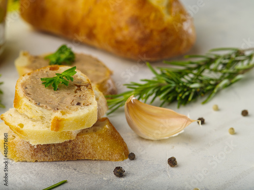 Sandwiches isolated on a white background - slices of a baguette with French foie gras, green parsley leaves, a clove of garlic, black pepper and a sprig of rosemary. Restaurant dish.