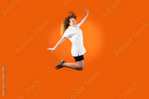 The young redhead woman in football uniform isolated jumping very high as a flight to the sun, fan human emotions concept.