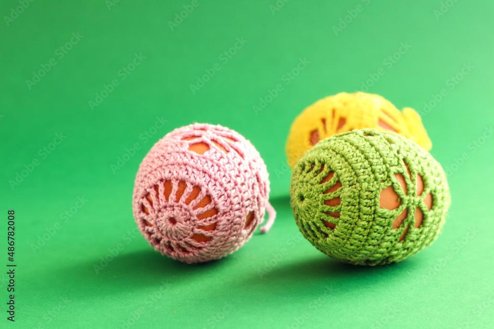 Easter cards: three Easter eggs decorated with a handmade knitted pattern on a green background, space for text Easter cards: three Easter eggs decorated with a handmade knitted pattern on a green background, space for text