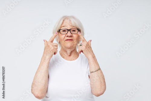 Photo of retired old lady in casual t-shirt and glasses light background