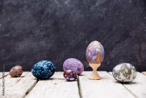 Original painted Easter eggs on a dark background. iolet, blue, gray Easter eggs with marbled transitions, painted with natural dyes. Space ornaments on food
