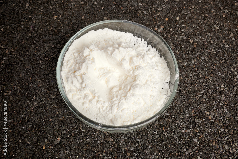 Cocaine powder in Petri dish on ruberoid textured surface. Dark gray textured background. Dark business of narcotic dealers. Chemical glassware with heroin flour. Toxic dust inside chemical dish. Cocaine powder in Petri dish on ruberoid textured surface. Dark gray textured background. Dark business of narcotic dealers. Chemical glassware with heroin flour. Toxic dust inside chemical dish.
