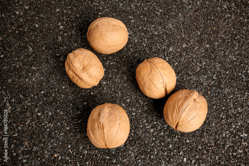 Greek nuts on ruberoid textured surface. Black textured background. Vegan diet concept. Natural oil source on a ground for breakfast. Vegetarian nutrition. Greek nuts inside shells. photo