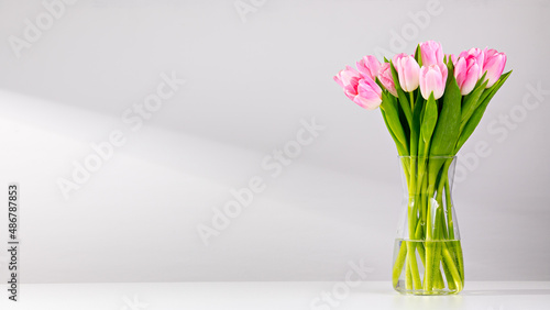 Pink tulips in a vase on a white table