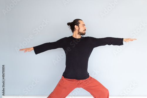 Young Caucasian long haired white man is performing yoga in a studio or house.