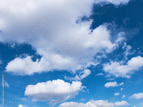 White fluffy clouds in a bright blue sky. Sky background. Cloudscape