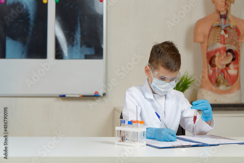 a boy in a medical uniform studies test tubes with tests in his office