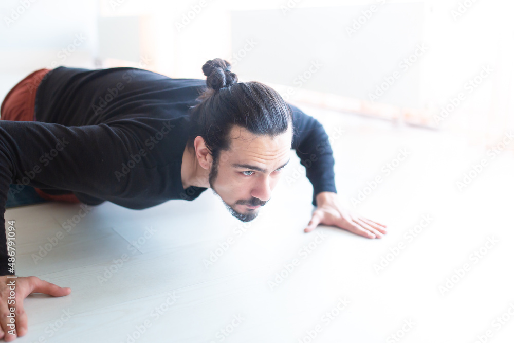 Young Caucasian long haired white man is performing yoga in a studio or house. Young Caucasian long haired white man is performing yoga in a studio or house.