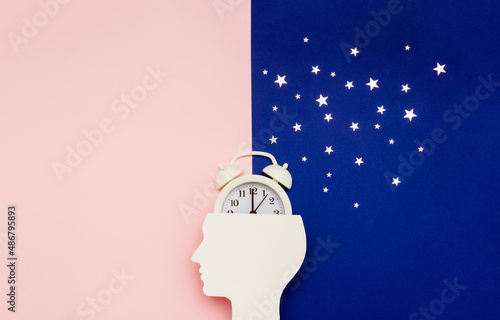 Silhouette of human and alarm clock on pink and blue backgrounds decorated with silver confetti. Human circadian rhythms concept. Copy space photo