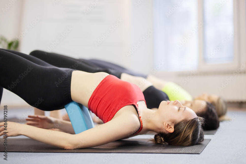 Three girls practicing yoga. Yoga instructor with her students meditating in a studio. Three girls practicing yoga. Yoga instructor with her students meditating in a studio.