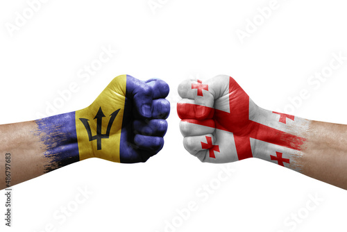 Two hands punch to each others on white background. Country flags painted fists, conflict crisis concept between barbados and georgia