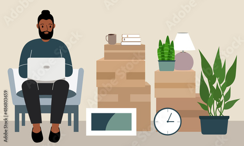 A man at home with a laptop sits in a chair. The concept of online registration of delivery of boxes, goods and assistance in moving.