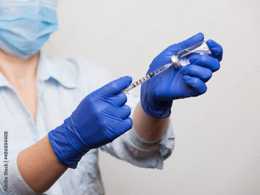 hands of a nurse in medical gloves dialing a vaccine or medicine for injection into the syringe hands of a nurse in medical gloves dialing a vaccine or medicine for injection into the syringe