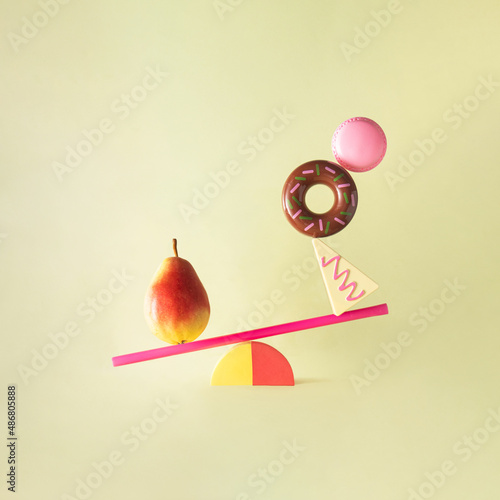 Creative balanced lifestyle concept. Minimalistic composition with sweets and fruit on pastel purple background. Eating healthy food idea.
