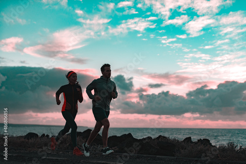 Runners couple athlete silhouette running in morning dusk in the dark by the coast. View of nature landscape and beach active people lifestyle