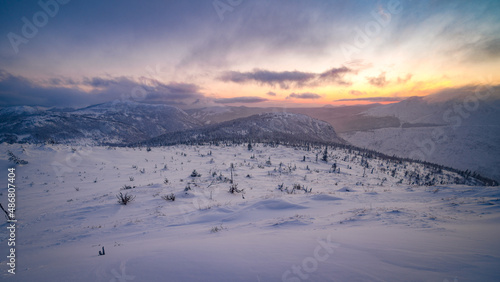 Colorful sky and sunlight as the sun sets under the horizon, over the snowy mountains of Gaspesie nationa park, QC' Canada