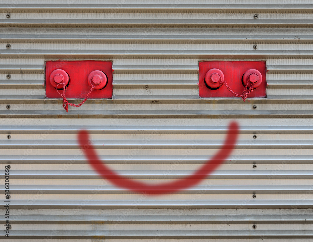 Decorative pattern of red smiley faces with graffiti on street building wall