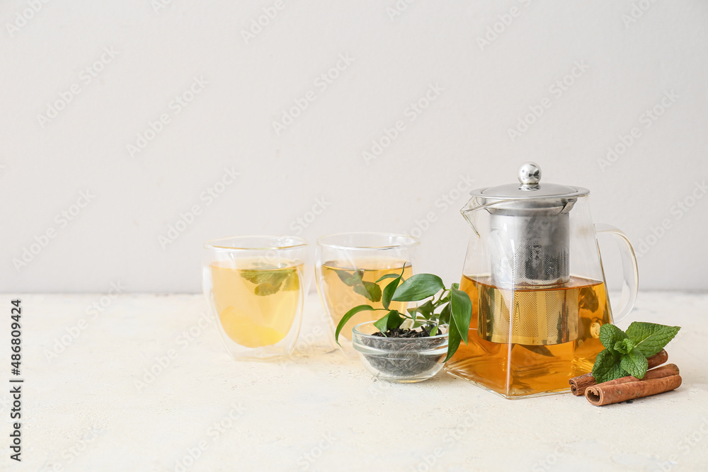 Teapot and glasses of tasty tea on light background Teapot and glasses of tasty tea on light background