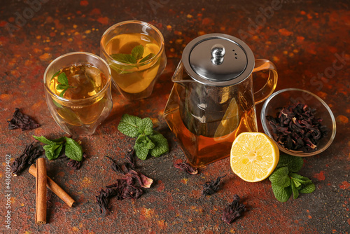 Teapot and glasses of tasty tea on grunge background