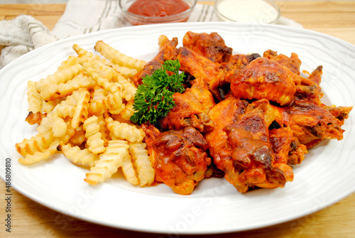A Platter of Spicy baked Buffalo Wings Served with French Fries