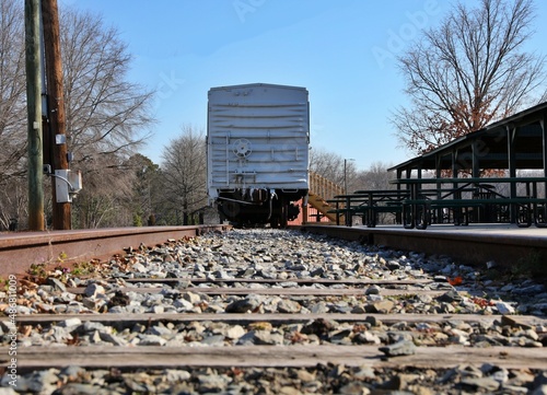 Looking between the tracks at a rail car parked at a station.  