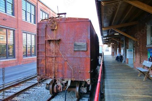 Vintage rusty rail car sitting on a track in front of a station.  