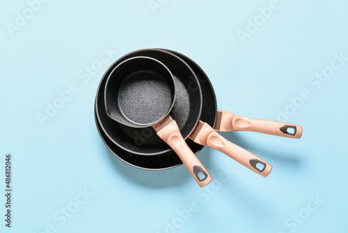 Frying pans and saucepan on color background