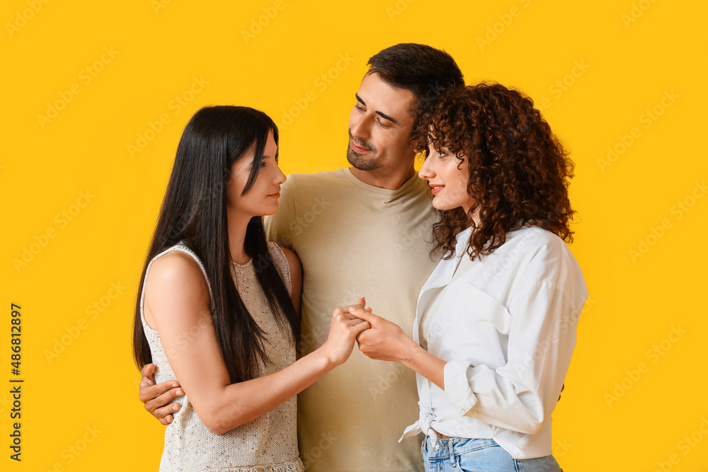 Man and two beautiful women on color background. Polyamory concept Man and two beautiful women on color background. Polyamory concept