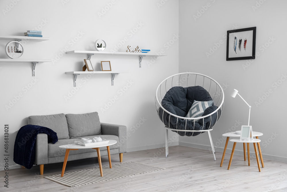 Obraz premium Interior of light living room with grey sofa, coffee tables and armchair