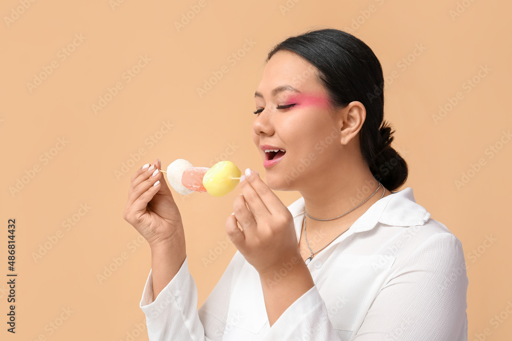 Beautiful Asian woman eating tasty Japanese mochi on color background Beautiful Asian woman eating tasty Japanese mochi on color background