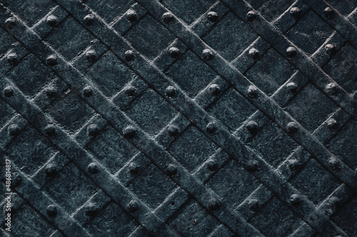 Old black metal door with a diamond pattern close-up. Vintage background closeup. Medieval forging technologies.