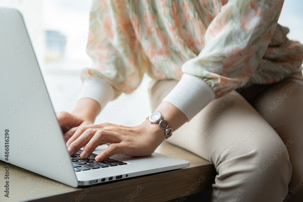 Naklejka premium Unrecognizable Asian young woman using laptop computer or notebook computer to search the news and information.